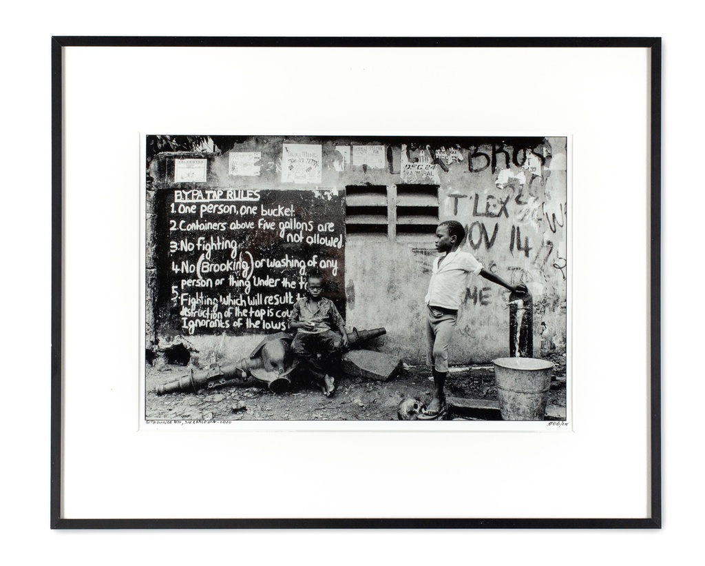 Freetown, Sierra Leone, mei 2000 Jongen bij waterpomp met huisregels